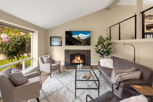 living room featuring wood finished floors, lofted ceiling, a tile fireplace, and baseboards
