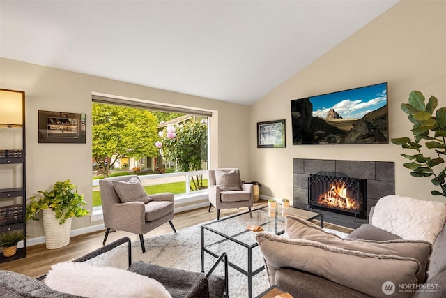 living room with a tile fireplace, wood finished floors, lofted ceiling, and baseboards