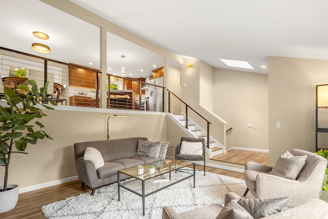 living area with wood finished floors, a skylight, baseboards, stairway, and recessed lighting