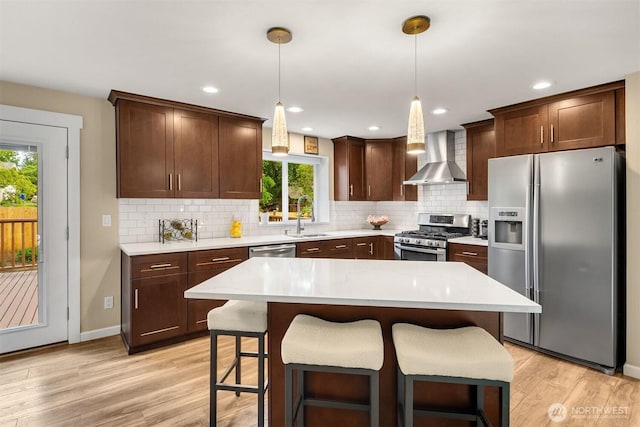 kitchen with appliances with stainless steel finishes, wall chimney range hood, a sink, plenty of natural light, and recessed lighting