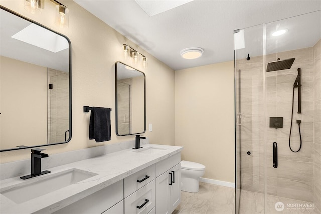 bathroom with a shower stall, toilet, marble look tiles, double vanity, and a skylight