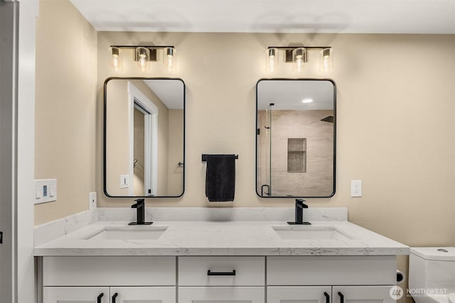 full bathroom featuring a shower stall, toilet, and double vanity