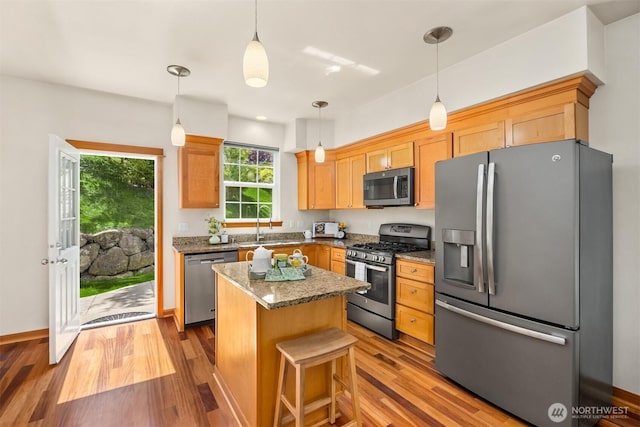 kitchen featuring stainless steel appliances, wood finished floors, a center island, and plenty of natural light
