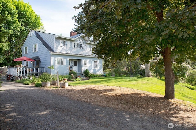 view of front of property with a chimney, a front yard, and a wooden deck