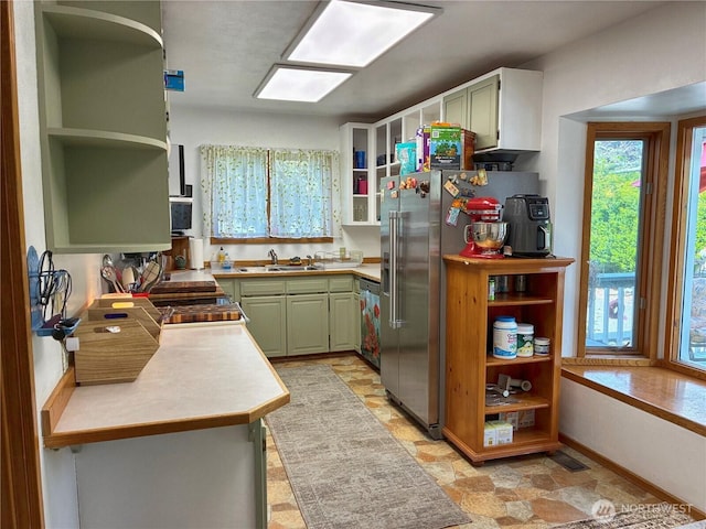 kitchen with open shelves, light countertops, stone finish flooring, and a sink