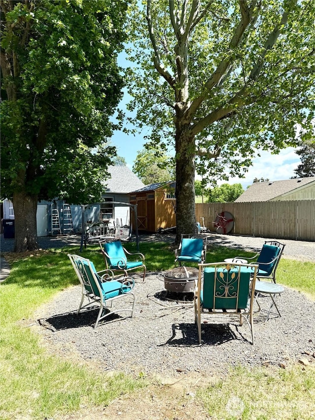 view of yard featuring an outdoor fire pit, a storage unit, an outbuilding, and a patio