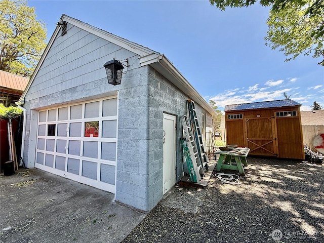 view of side of home featuring an outdoor structure, a shed, and concrete block siding