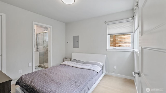 bedroom with baseboards, light wood-style flooring, electric panel, and connected bathroom