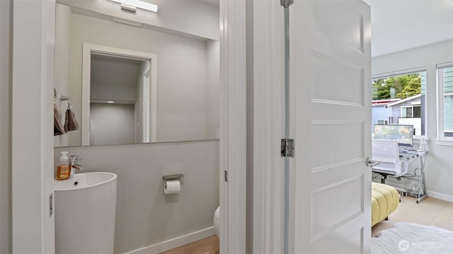 bathroom featuring toilet, baseboards, and wood finished floors