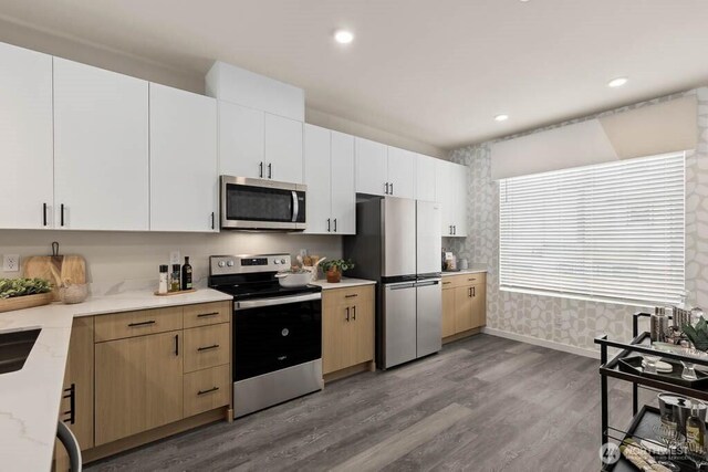14707 87th Ave SE Unit Ff5, Snohomish, WA 98296 - kitchen featuring stainless steel appliances, wood finished floors, baseboards, wallpapered walls, and white cabinets