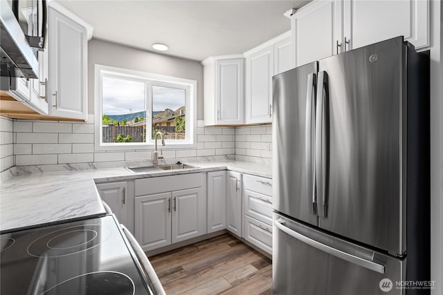 1819 Springwater Ave, Wenatchee, WA 98801 - kitchen with freestanding refrigerator, a sink, range with electric stovetop, white cabinetry, and light wood-style flooring