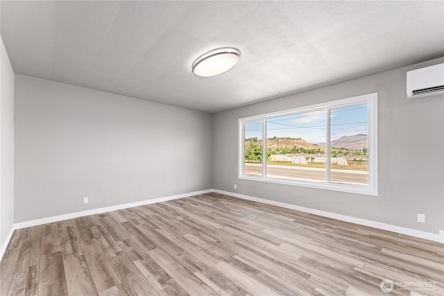 1819 Springwater Ave, Wenatchee, WA 98801 - spare room featuring a wall unit AC, wood finished floors, baseboards, and a textured ceiling