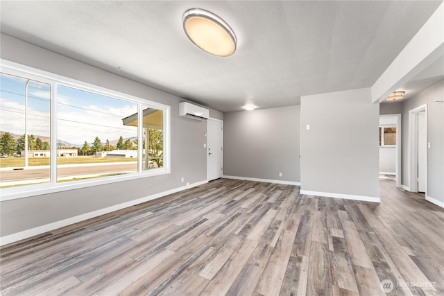 1819 Springwater Ave, Wenatchee, WA 98801 - unfurnished living room featuring a wall mounted air conditioner, wood finished floors, baseboards, and a textured ceiling