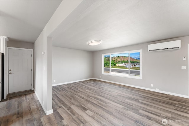 1819 Springwater Ave, Wenatchee, WA 98801 - unfurnished living room with a wall mounted AC, wood finished floors, and baseboards