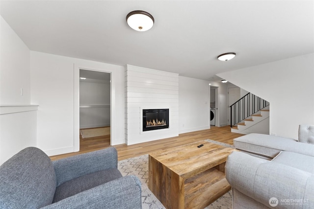 11242 Fremont Ave N Unit B, Seattle, WA 98133 - living area featuring light wood-style flooring, stairs, a fireplace, baseboards, and stacked washer / dryer