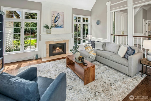 8150 Evergreen Ln, Mercer Island, WA 98040 - living room featuring lofted ceiling, healthy amount of natural light, a tiled fireplace, wood finished floors, and wainscoting