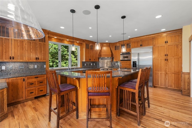 4155 212th Way SE, Sammamish, WA 98075 - kitchen featuring stainless steel built in refrigerator, light wood-style floors, custom range hood, brown cabinetry, and backsplash