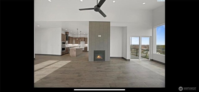 3312 Bing St, West Richland, WA 99353 - unfurnished living room featuring ceiling fan, a towering ceiling, a tile fireplace, baseboards, and recessed lighting