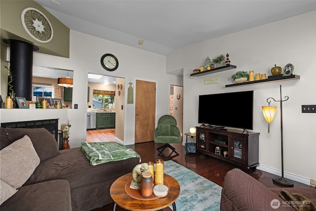 living area featuring wood finished floors, lofted ceiling, and baseboards