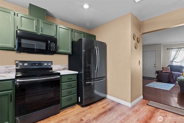kitchen featuring black appliances, green cabinetry, light countertops, and light wood-style floors