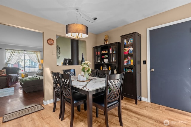 dining space with light wood-type flooring and baseboards
