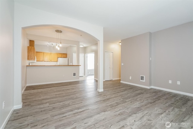 5400 Harbour Pointe Blvd Unit E102, Mukilteo, WA 98275 - unfurnished living room with light wood finished floors, baseboards, arched walkways, and a chandelier