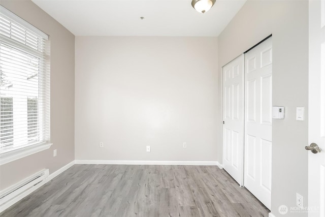 5400 Harbour Pointe Blvd Unit E102, Mukilteo, WA 98275 - unfurnished bedroom with a baseboard radiator, light wood finished floors, a closet, and baseboards