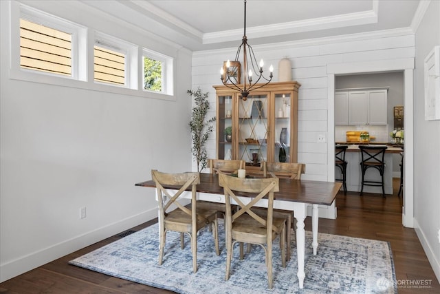 dining area with a chandelier, crown molding, dark wood-style floors, a tray ceiling, and baseboards