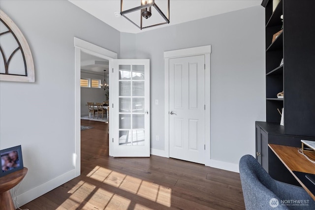 home office with a chandelier, wood finished floors, and baseboards