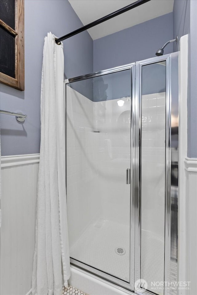 bathroom with a shower stall and wainscoting