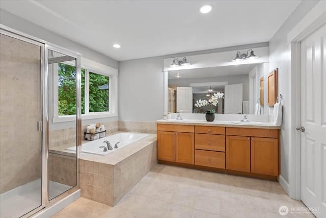 bathroom with a stall shower, tile patterned floors, a bath, double vanity, and recessed lighting