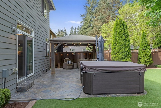 view of patio with a hot tub, a gazebo, and a fenced backyard