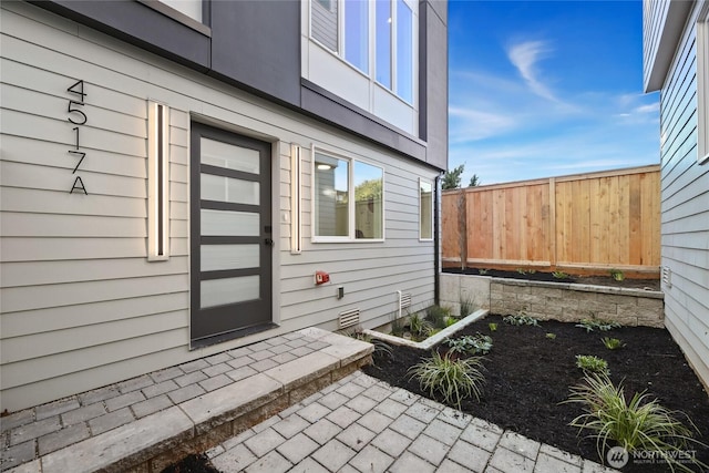 view of exterior entry featuring fence and a patio