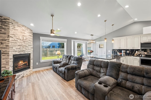 626 Duck Lake Dr SE, Ocean Shores, WA 98569 - living room with light wood-type flooring, vaulted ceiling, a stone fireplace, ceiling fan, and recessed lighting