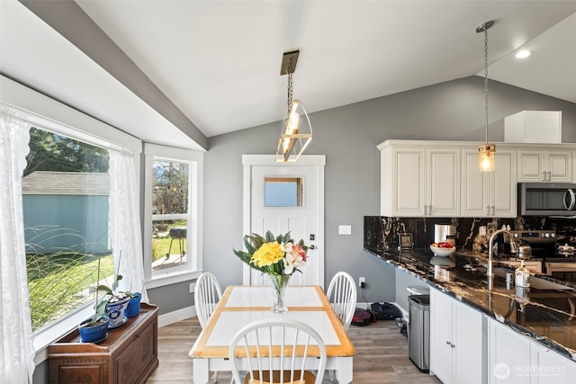626 Duck Lake Dr SE, Ocean Shores, WA 98569 - kitchen with stainless steel appliances, vaulted ceiling, light wood-style flooring, tasteful backsplash, and decorative light fixtures