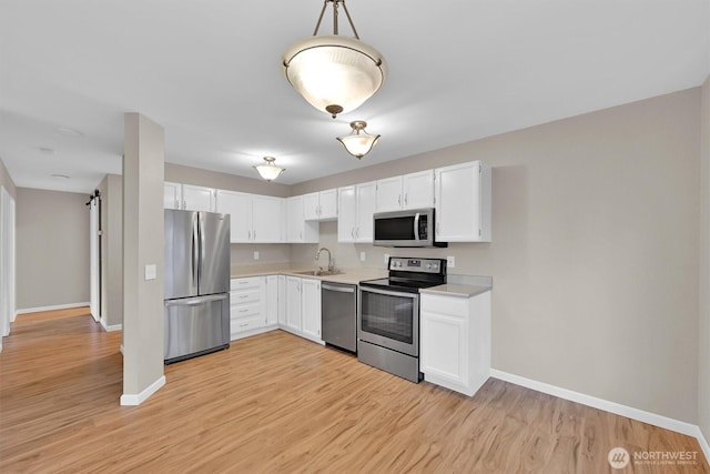 1175 Harrington Pl NE Unit 101, Renton, WA 98056 - kitchen with appliances with stainless steel finishes, baseboards, light countertops, white cabinetry, and light wood-style floors