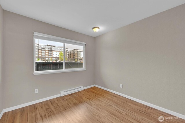 1175 Harrington Pl NE Unit 101, Renton, WA 98056 - unfurnished room with wood finished floors, baseboards, and a baseboard radiator