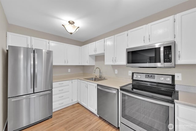 1175 Harrington Pl NE Unit 101, Renton, WA 98056 - kitchen with stainless steel appliances, a sink, light countertops, white cabinets, and light wood-type flooring