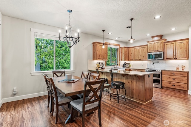 dining space with dark wood-style flooring, healthy amount of natural light, a chandelier, baseboards, and a textured ceiling
