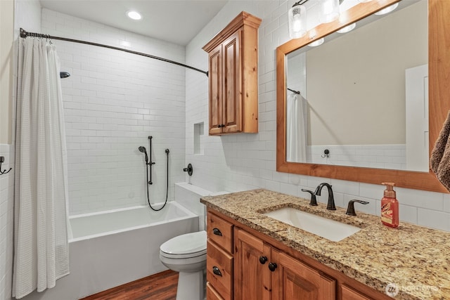 full bathroom featuring tile walls, wood finished floors, shower / bathtub combination with curtain, toilet, and vanity