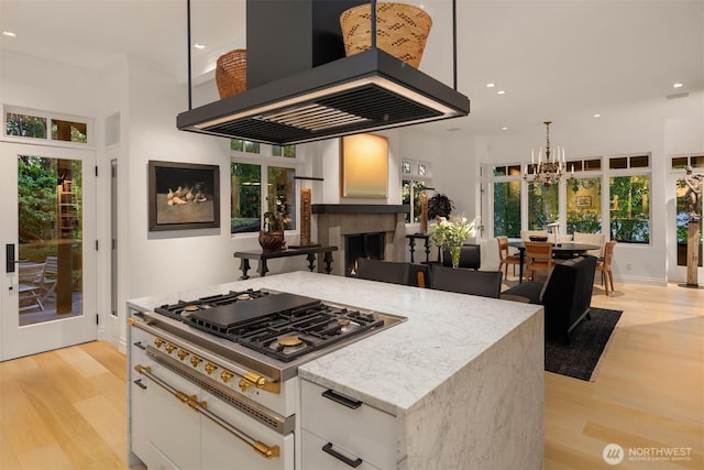 10208 47th Ave SW, Seattle, WA 98146 - kitchen with island exhaust hood, white cabinetry, light wood-style flooring, stainless steel gas stovetop, and recessed lighting