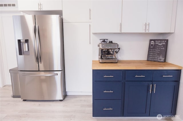21833 127th Ave SE, Snohomish, WA 98296 - kitchen with stainless steel fridge, blue cabinetry, light wood-type flooring, white cabinets, and wooden counters