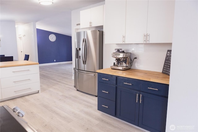 21833 127th Ave SE, Snohomish, WA 98296 - kitchen with stainless steel fridge, blue cabinetry, butcher block counters, white cabinetry, and light wood-style flooring