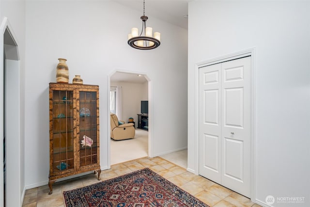 805 E Pacificview Dr, Bellingham, WA 98229 - entrance foyer featuring arched walkways, high vaulted ceiling, a chandelier, light tile patterned floors, and baseboards