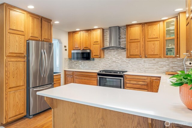 805 E Pacificview Dr, Bellingham, WA 98229 - kitchen with appliances with stainless steel finishes, wall chimney exhaust hood, a peninsula, light countertops, and tasteful backsplash