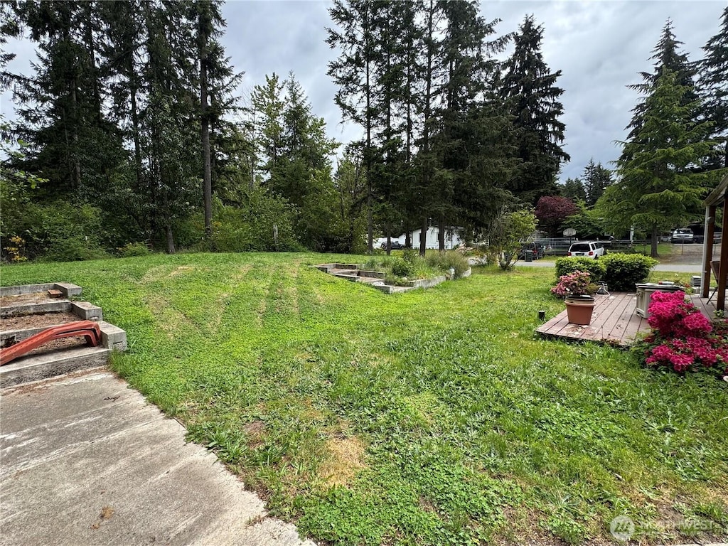 view of green lawn featuring a deck