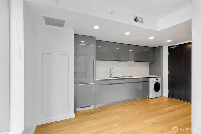 1808 Minor Ave Unit 301, Seattle, WA 98101 - kitchen featuring washer / clothes dryer, gray cabinetry, a sink, modern cabinets, and light wood-style flooring