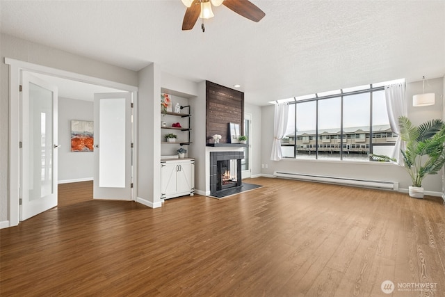7 Lake Bellevue Dr Unit 109, Bellevue, WA 98005 - unfurnished living room featuring a baseboard heating unit, wood finished floors, a ceiling fan, and a fireplace