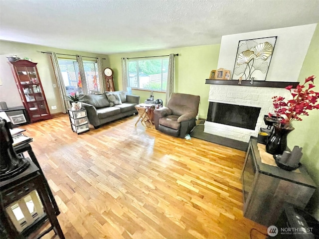 517 W St SE, Tumwater, WA 98501 - living room featuring wood finished floors, plenty of natural light, a stone fireplace, a textured ceiling, and baseboards