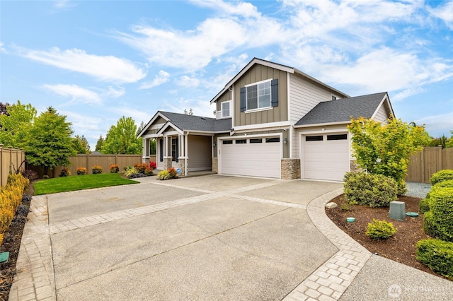 view of front facade featuring board and batten siding, fence, concrete driveway, stone siding, and a garage